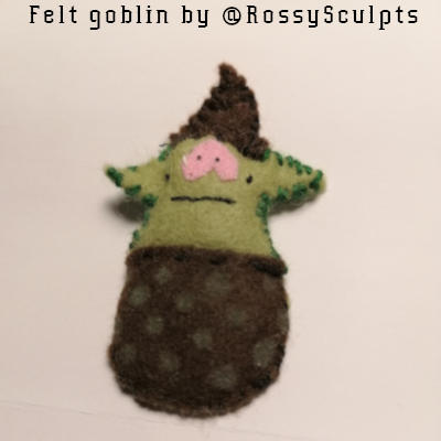 Goblin made of felt has a brown body and hat, light green skin, and a pink snout nose.